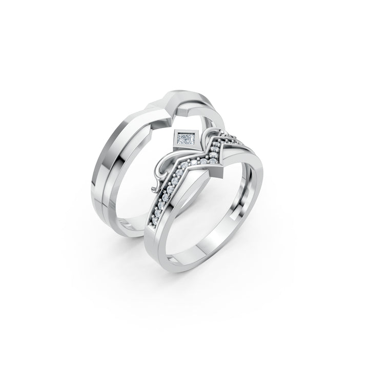 La Couronne à Deux, două verighete în V, un model cu diamante și bucle de metal în formă de coroană și un model fără diamante, vedere oblică, cu inelele suprapuse, metal alb.