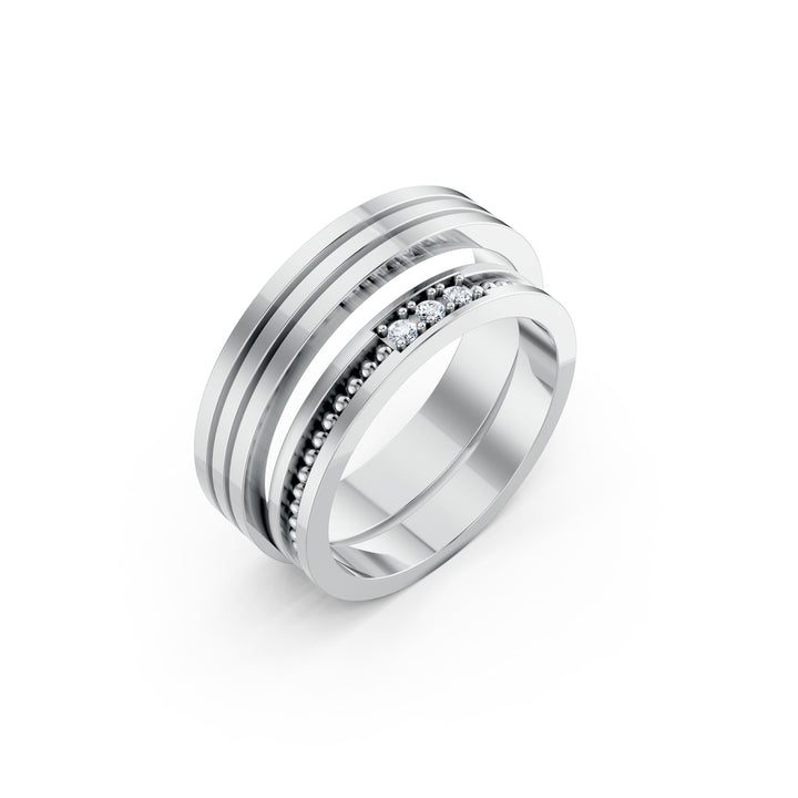 Les Trois Instants, două verighete, una cu trei diamante centrale și granule de metal, cealaltă cu două canale paralele, vedere oblică, cu inelele suprapuse, metal alb.