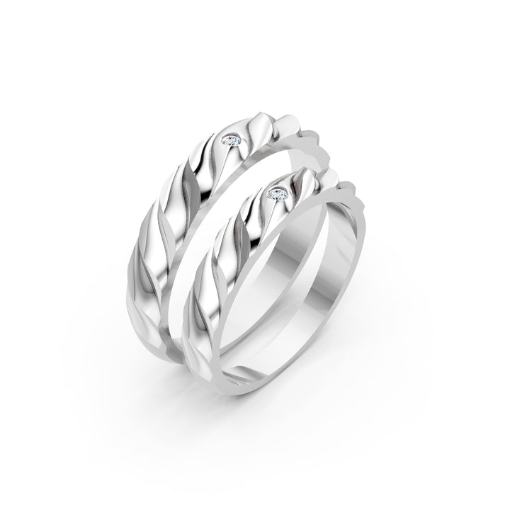 La Tresse des Jours, două verighete cu relief oblic, cu aspect de împletitură, și câte un diamant rotund, vedere oblică, cu inelele suprapuse, metal alb.